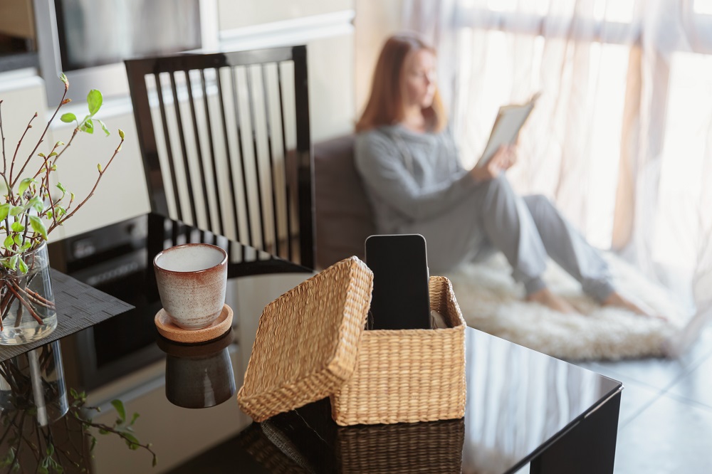 Frau-liest-ein-Buch-und-geniesst-ihre-handyfreie-Zeit-in-einem-Korb-liegt-das-Smartphone